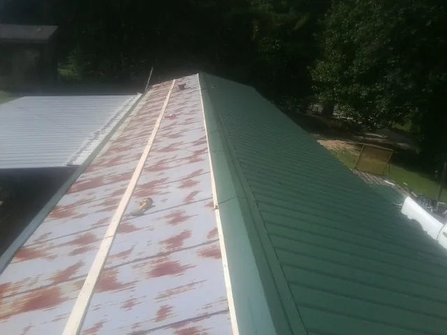Old rusted panels beside newly installed green metal roofing — Wind Damage Roof Repair by Roofing Brothers in Kittery