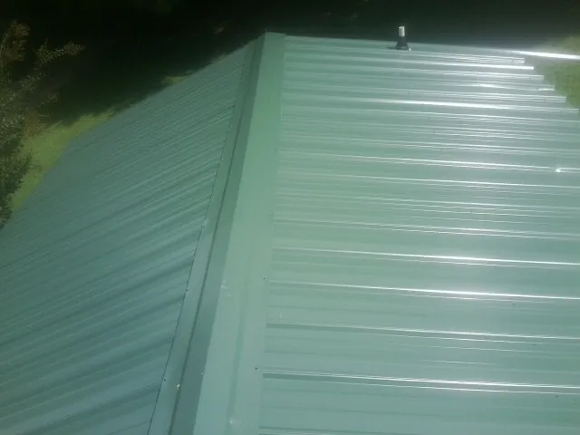 New green metal panels meeting at the ridge of a roof — Flat Roof Repair work by our crew in Kittery