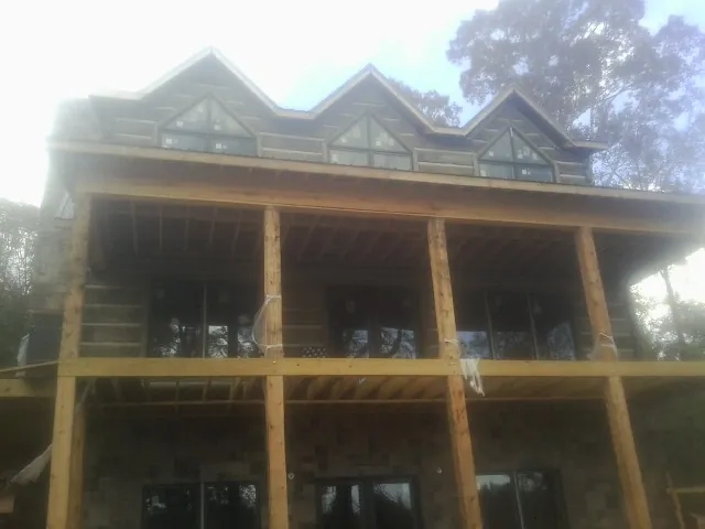 Dormers and porch framing on a large log home under construction — Roof Coating work by our crew in Kittery