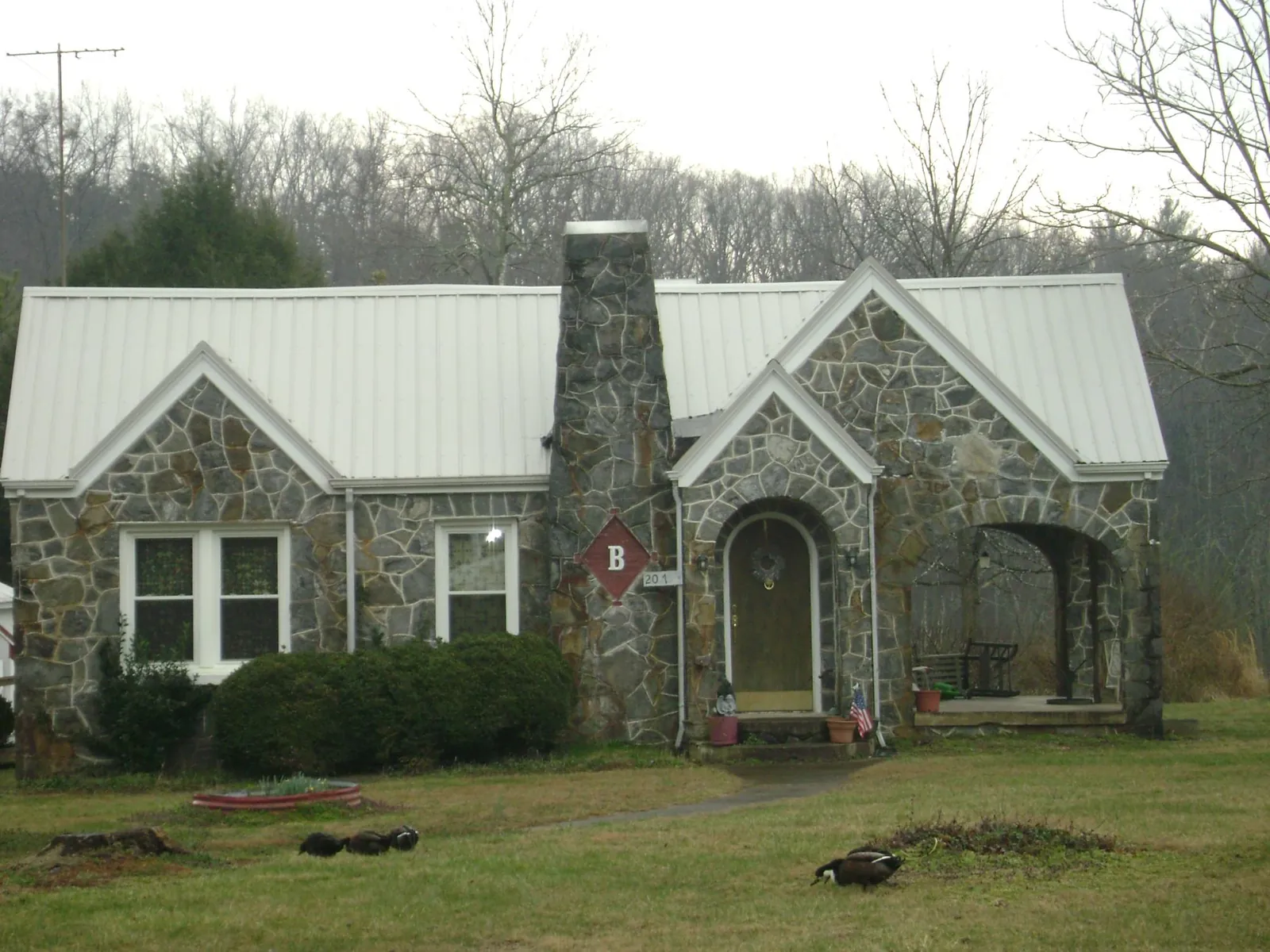 White metal roof on a stone cottage with steep gables in Kittery