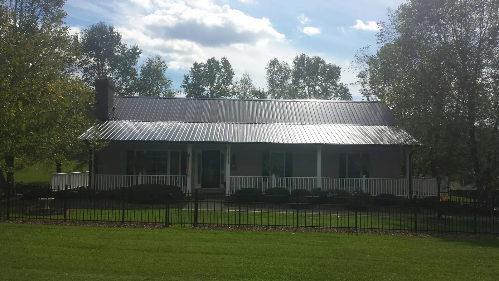 Gray metal roof on a brick ranch with a full width front porch — Gutter Guard Installation work by our crew in Kittery