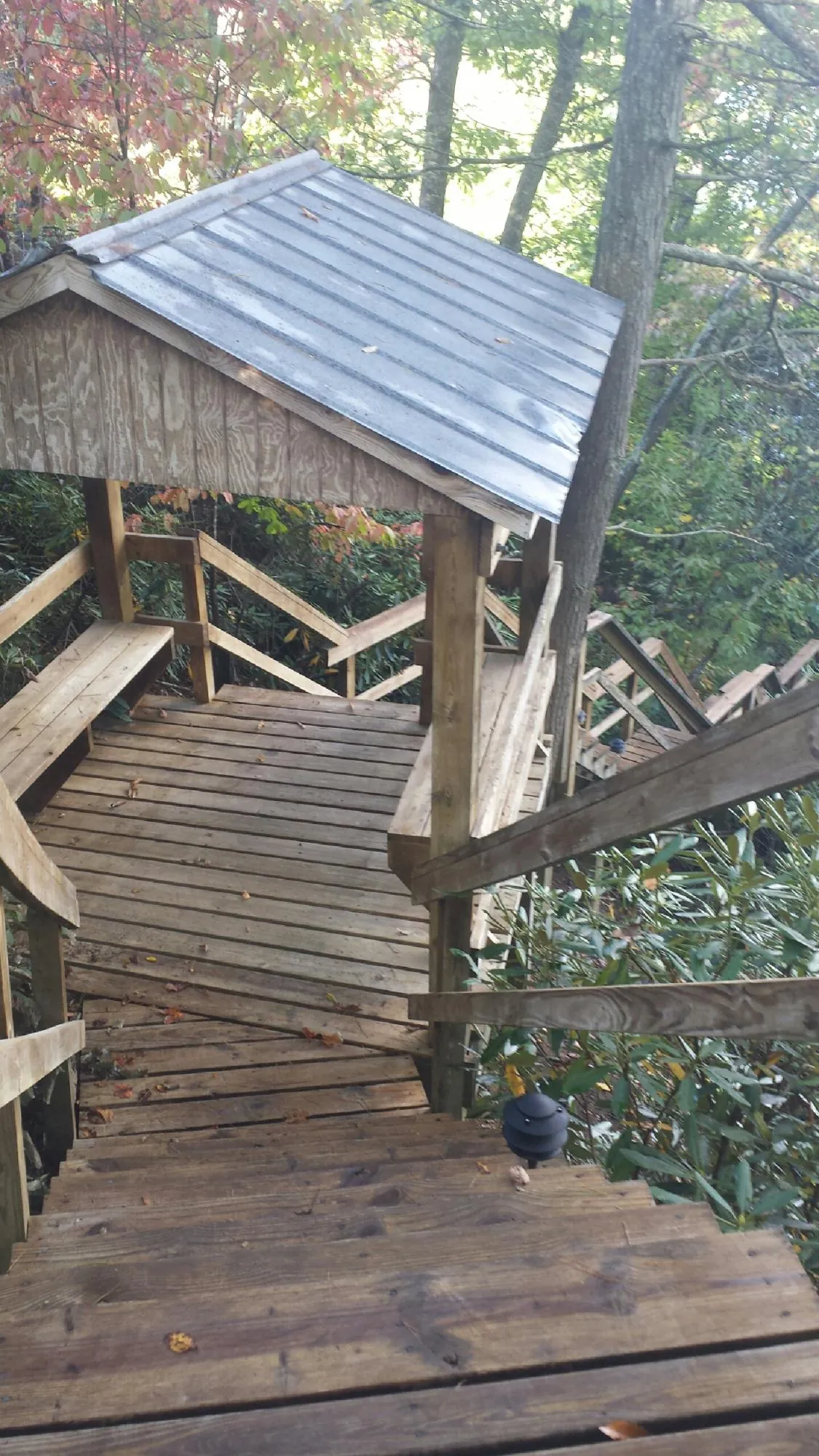 Metal roofed shelter over wooden steps on a wooded walkway — Skylight Repair & Installation work by our crew in Kittery
