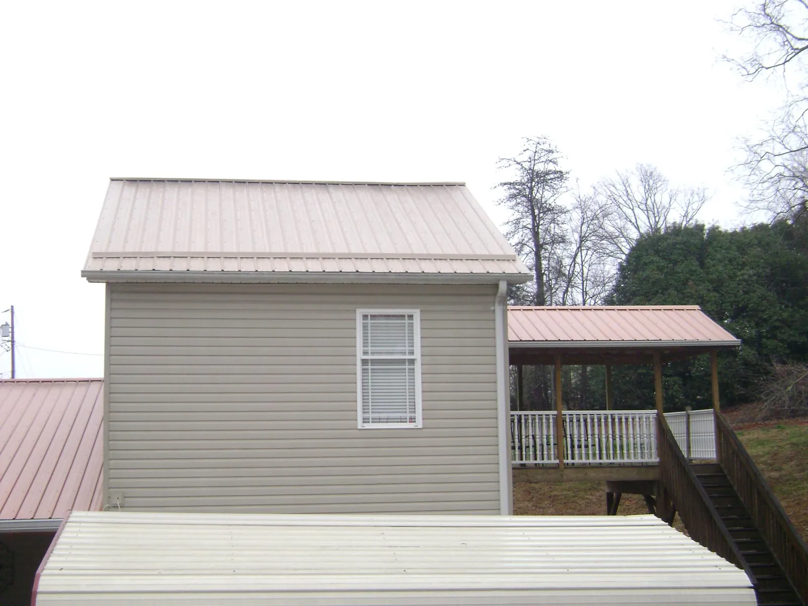 Tan metal roofs on a two story addition and attached porch, from a Roof Replacement job in Kittery