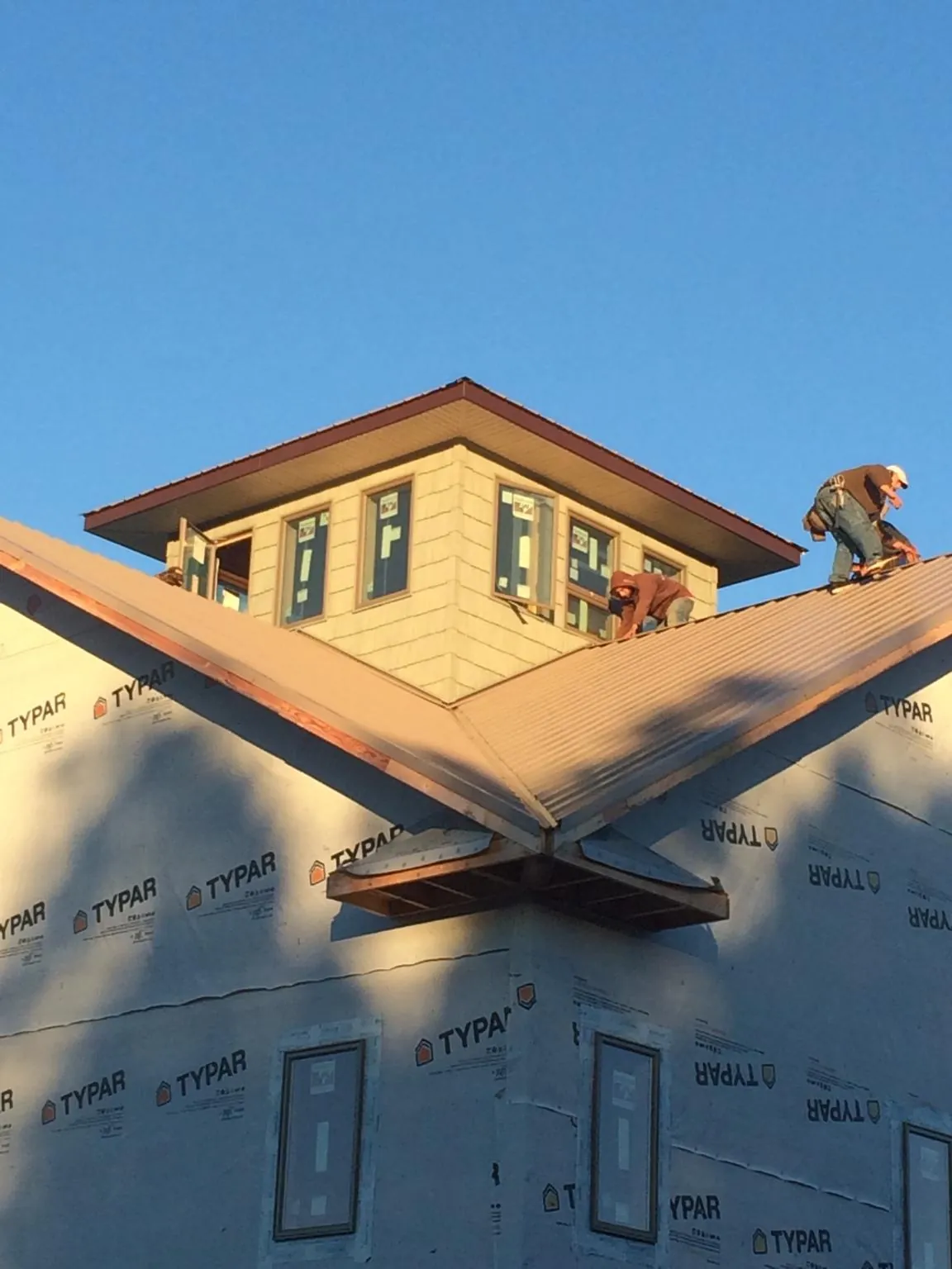 Roofers working around a rooftop cupola on a new metal roof at sunset — Roof Waterproofing in Kittery by Roofing Brothers